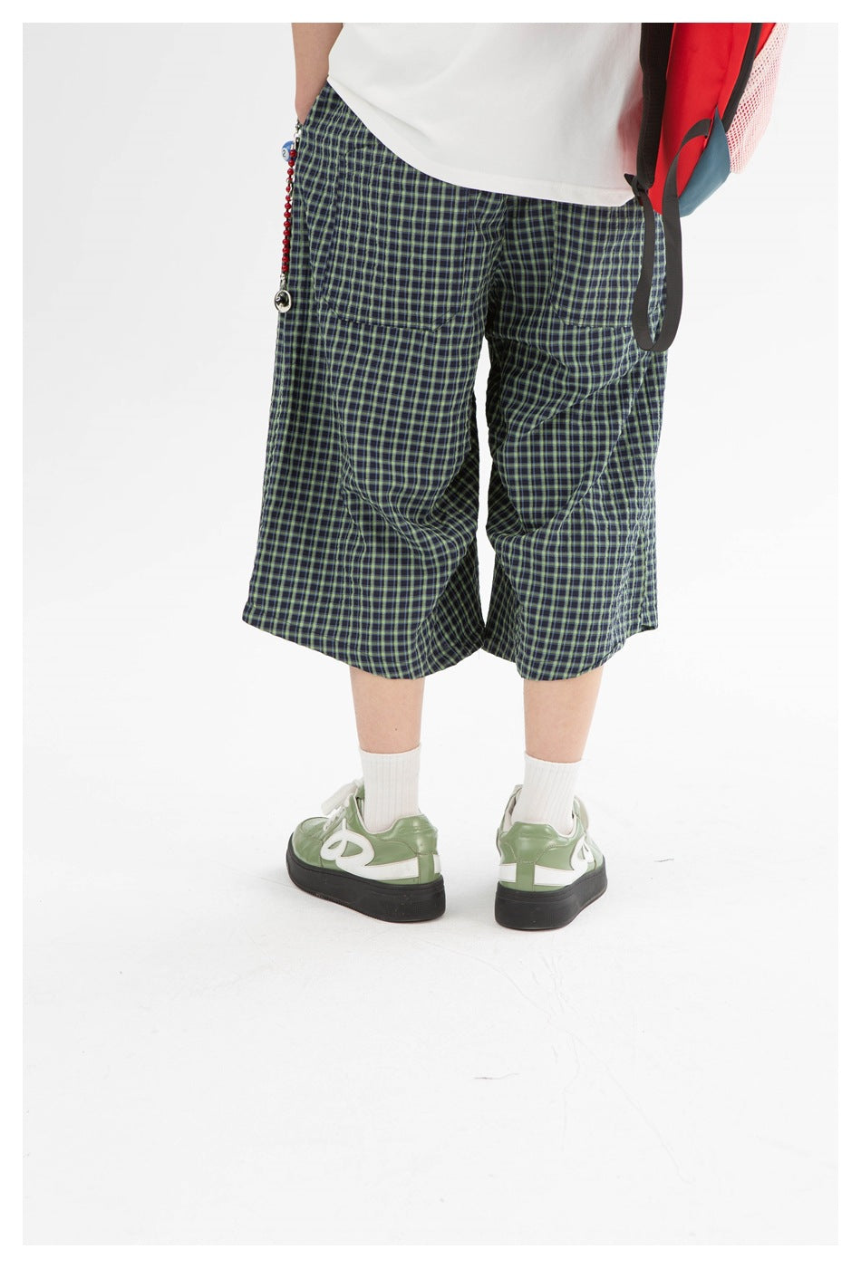 Rear close view of navy-and-green plaid shorts with two back pockets, worn with a white shirt.