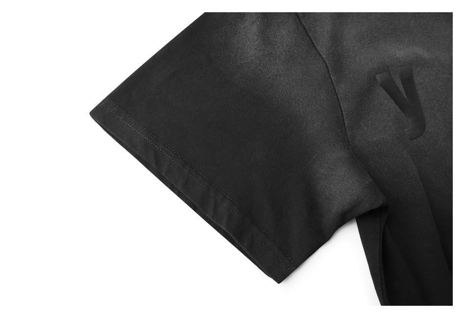 Close-up of a black short sleeve with a stitched hem and a subtle dark V-shaped mark on the garment.