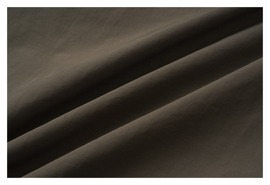 Close-up of dark brown fabric arranged in diagonal folds with a subtle fine texture.