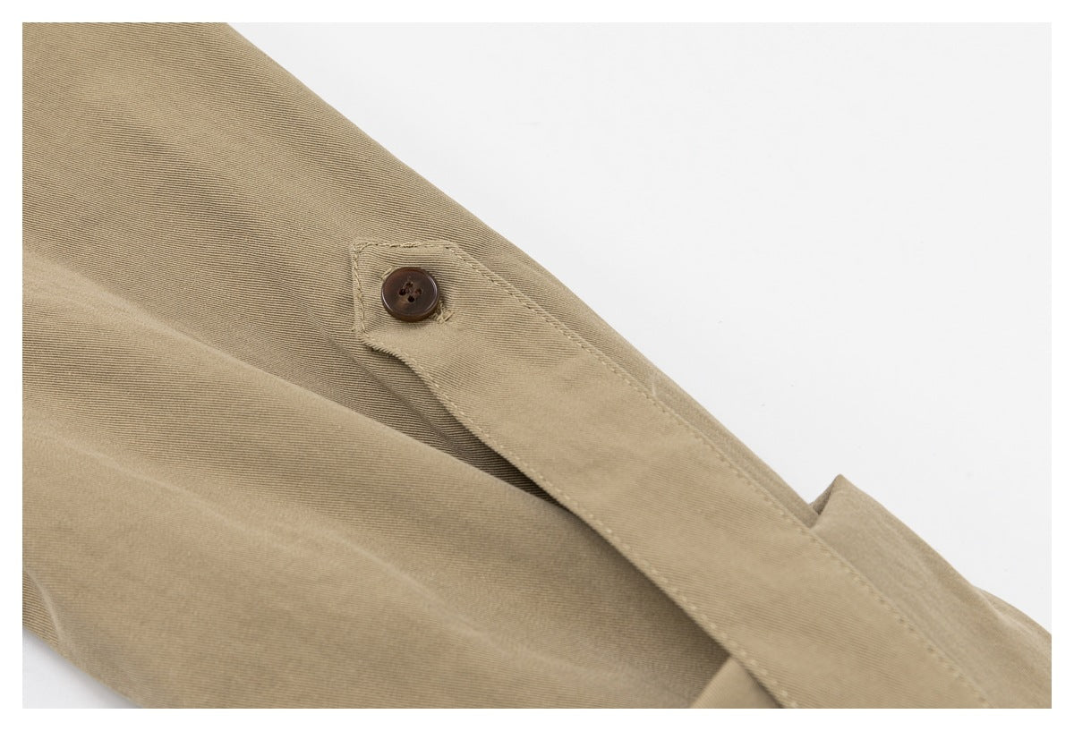 Close-up of beige garment fabric with a stitched button tab and dark brown button.