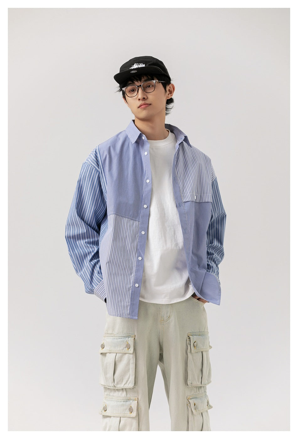 Model wearing the blue striped patchwork shirt open over a white tee with light cargo pants, front view