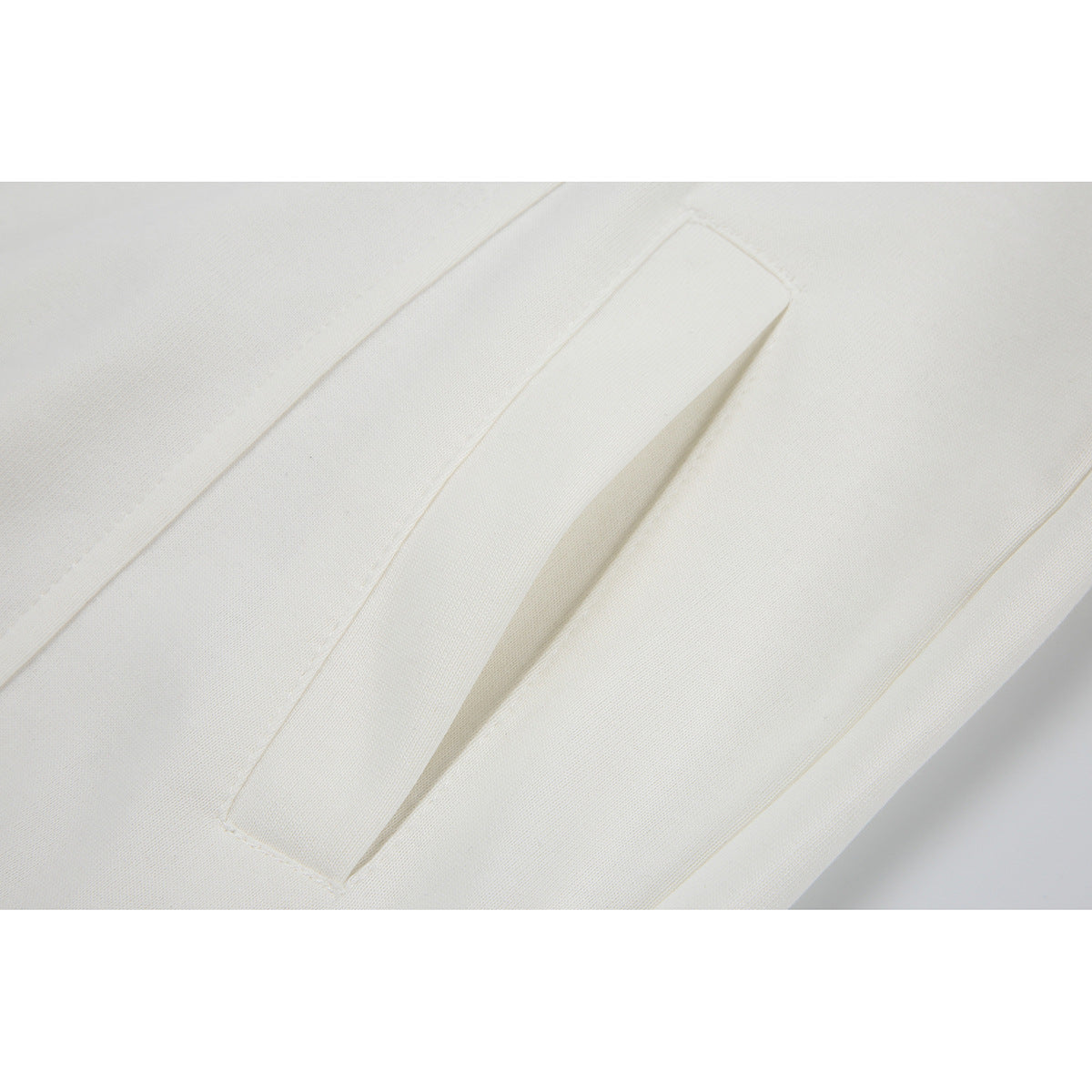 Close-up of a white garment showing a long, narrow welt pocket.