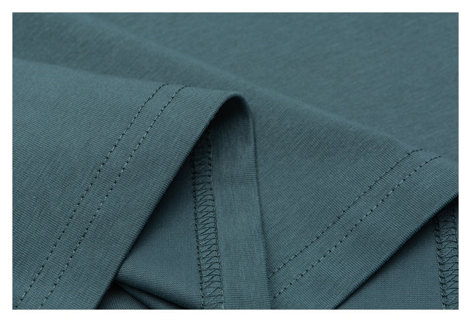 Close-up of overlapping teal garment hems with double stitching and finished seams.