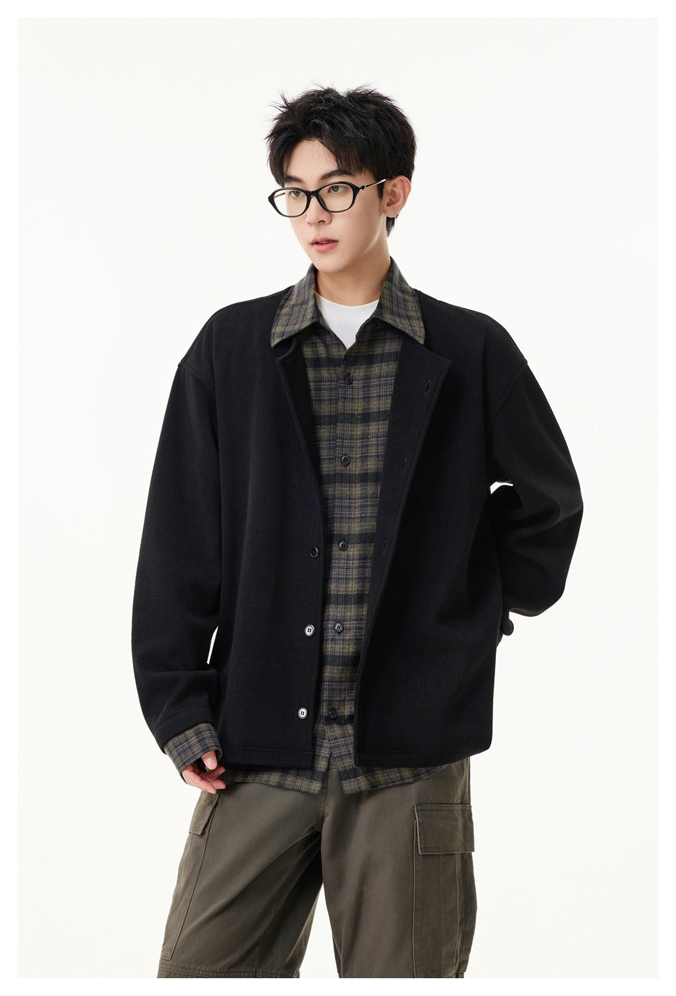 Front view of a model wearing a black button-front jacket over a dark plaid shirt and olive cargo pants.