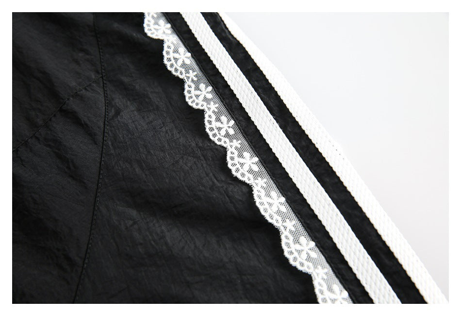 Close-up of black fabric with white floral lace edging and two braided white stripes.