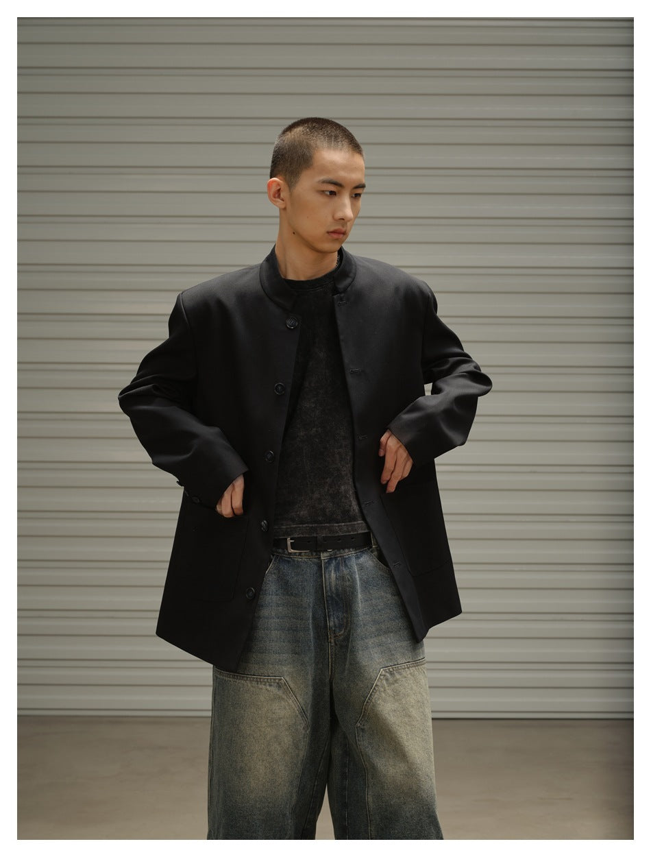 Closer view of a model wearing an open black stand-collar jacket with large front pockets and faded denim shorts.