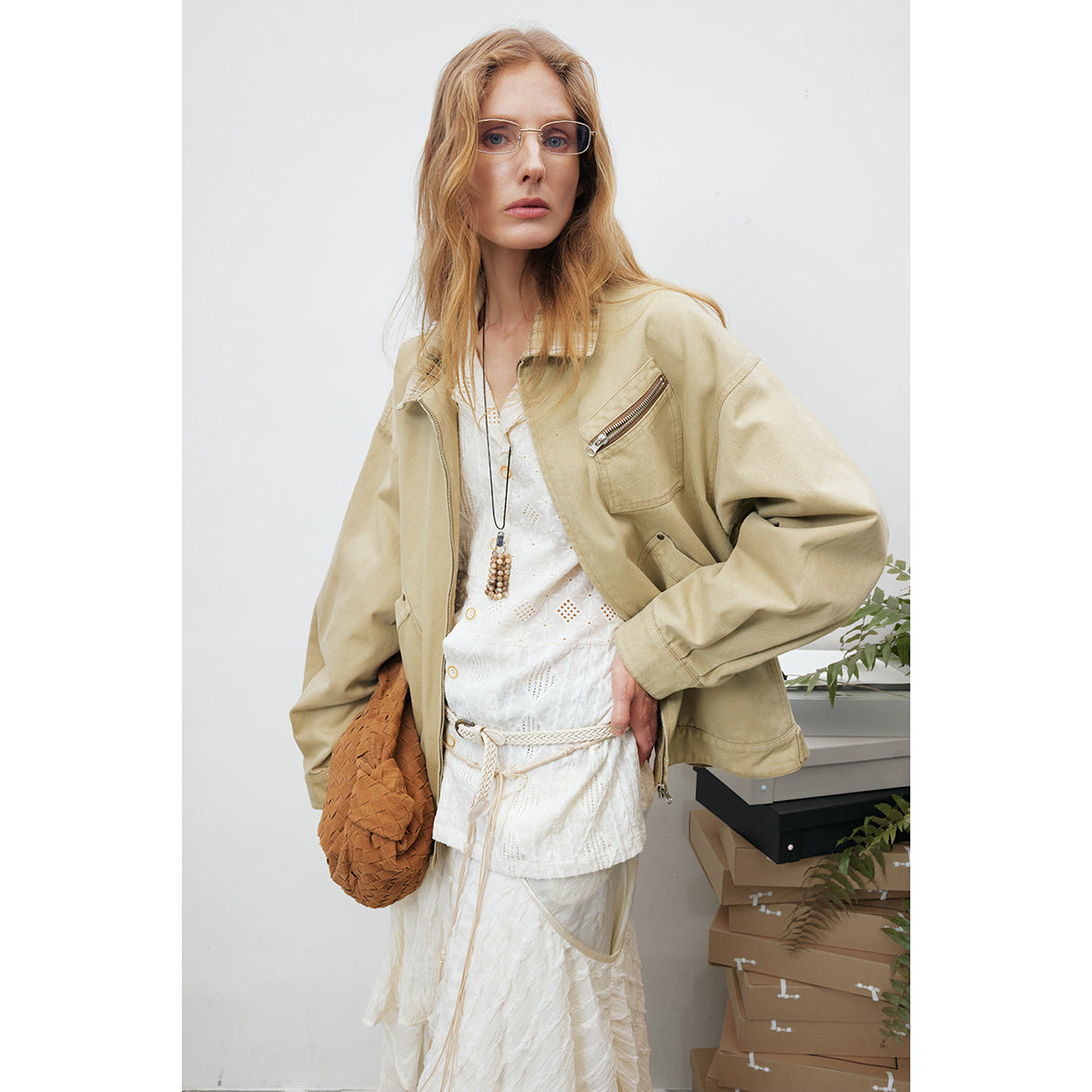 Three-quarter view of a model in a beige jacket with a zip chest pocket and roomy sleeves.