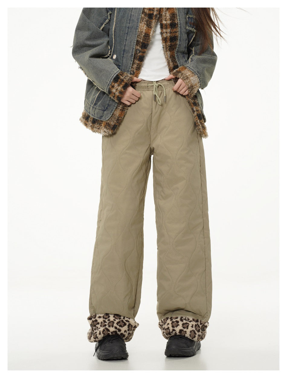 Model with hands on waist wearing green quilted wide-leg pants with leopard cuffs and a denim jacket