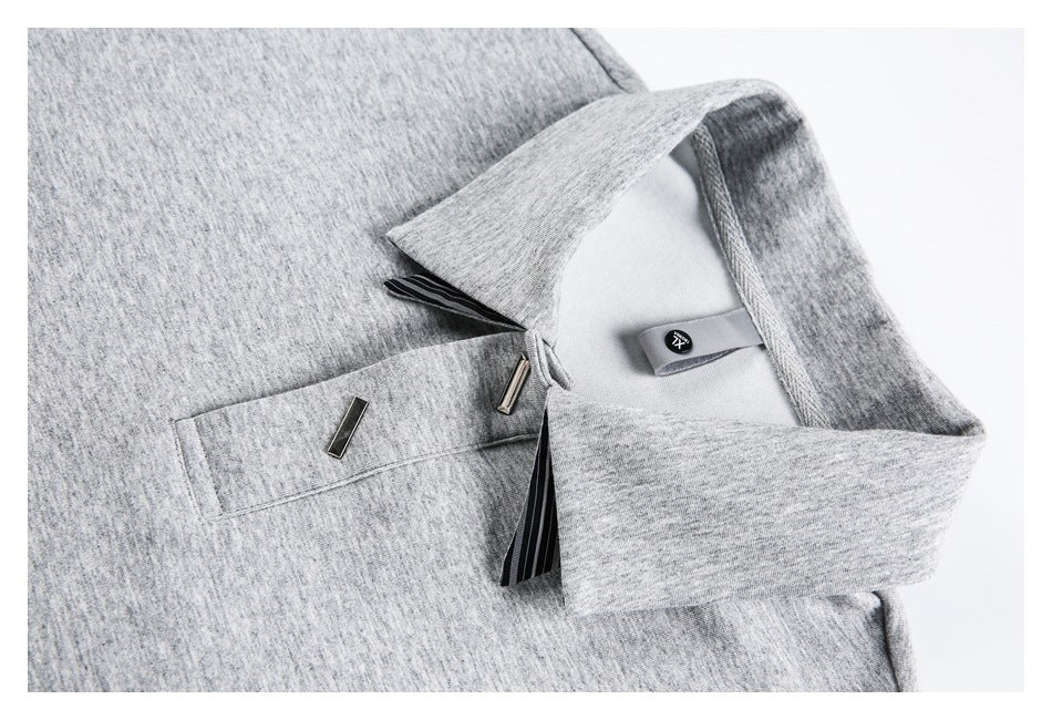 Close-up of a heather-gray collared shirt with a chest pocket, striped trim and small metal accents.