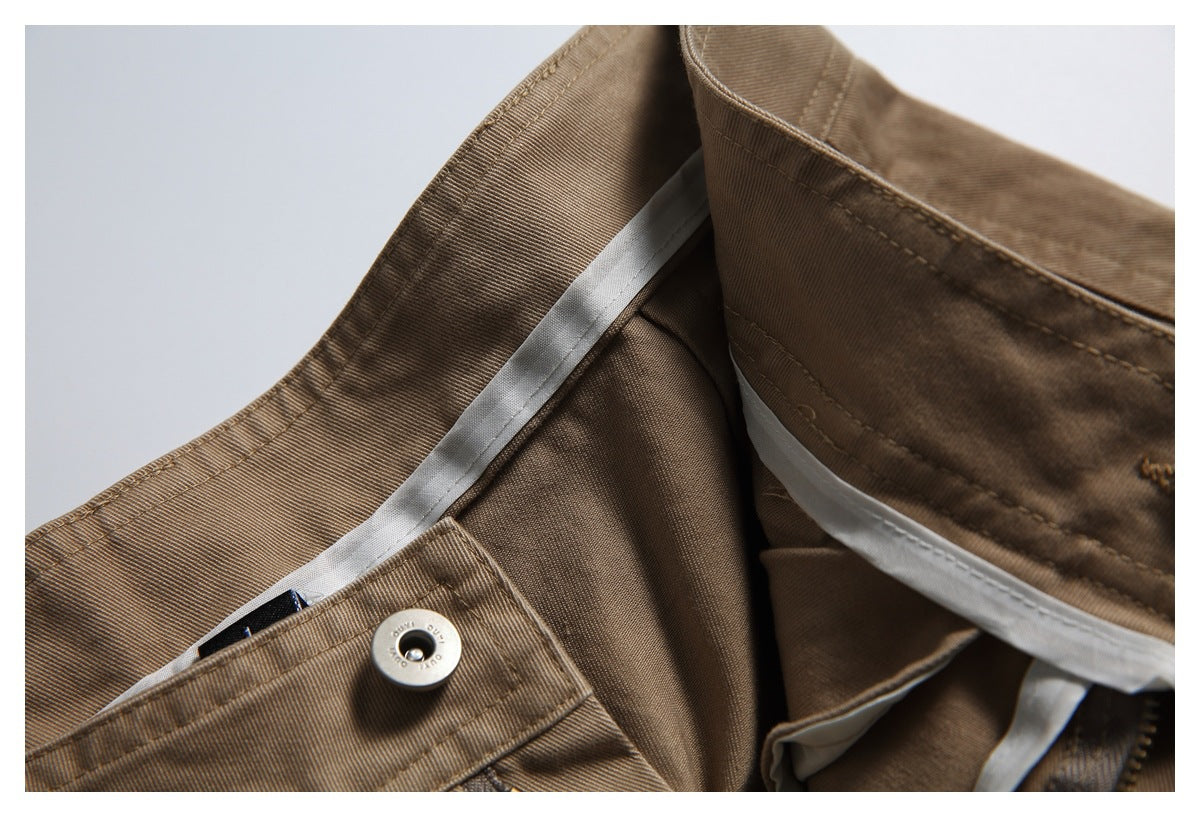 Close-up of brown garment waistband with a metal button, belt loops and light-colored inner trim.
