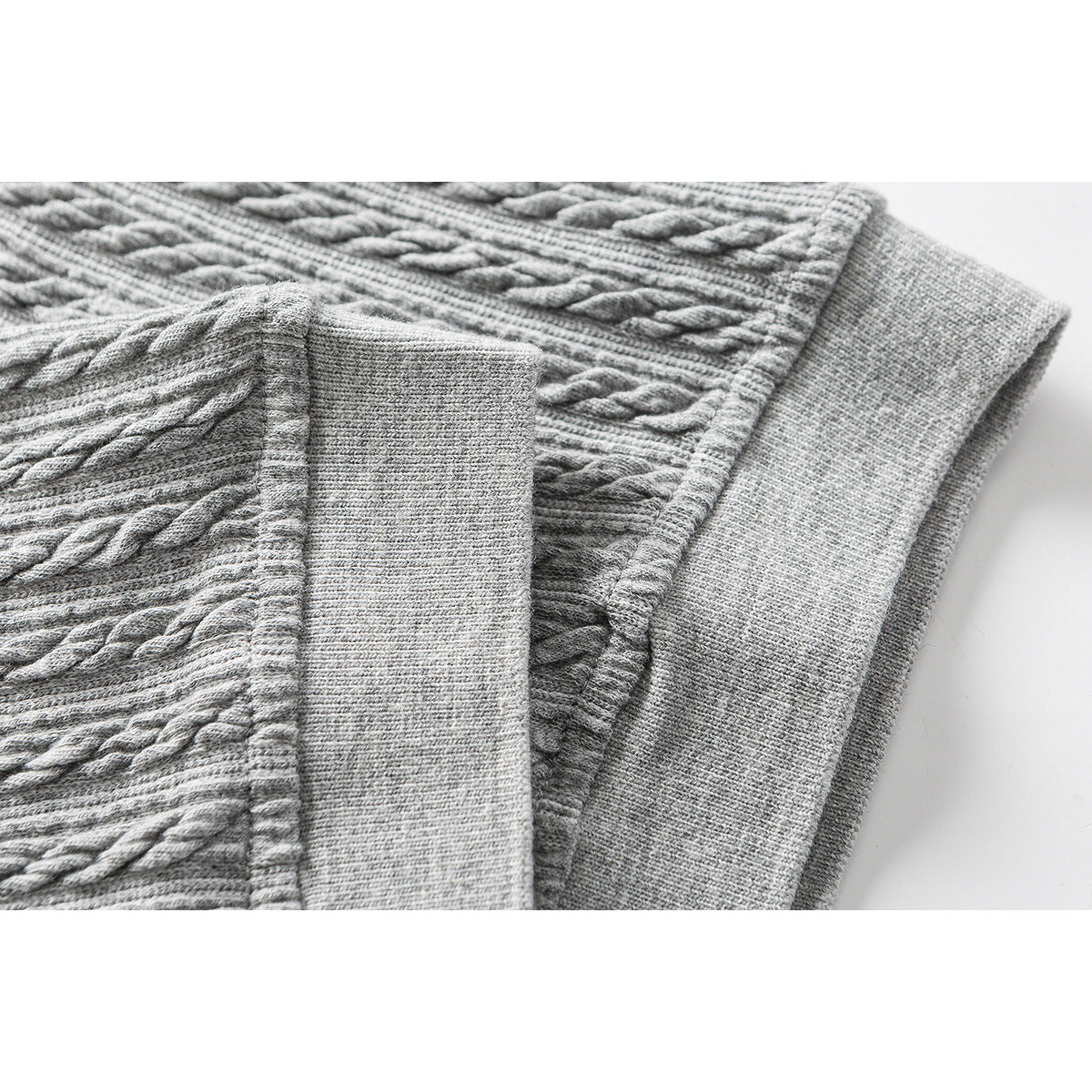 Close-up of a gray cable-textured polo shirt showing its ribbed sleeve cuff and hem.