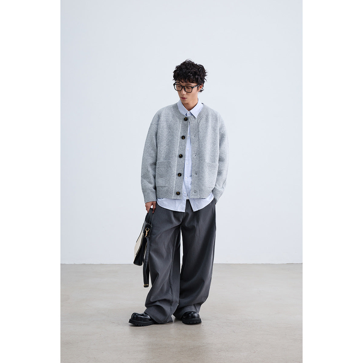 Model wearing a light gray button-front cardigan with ribbed trim and patch pockets, styled over a striped shirt.