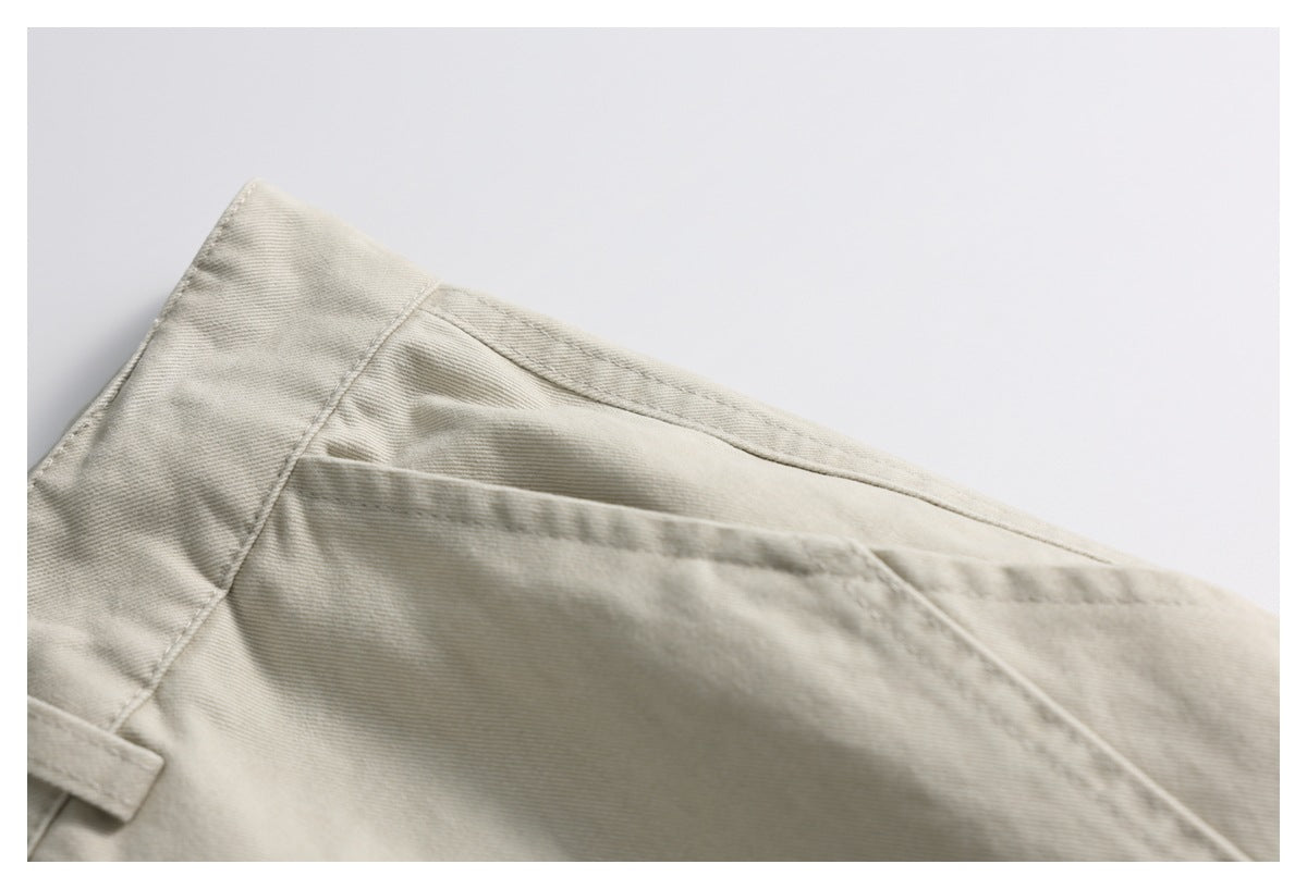 Close-up of light beige trousers with a diagonal pocket seam and a belt loop.