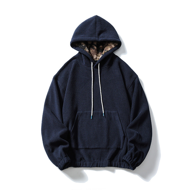 Navy fleece-like pullover hoodie with kangaroo pocket, white drawcords and patterned plush hood lining, flat lay