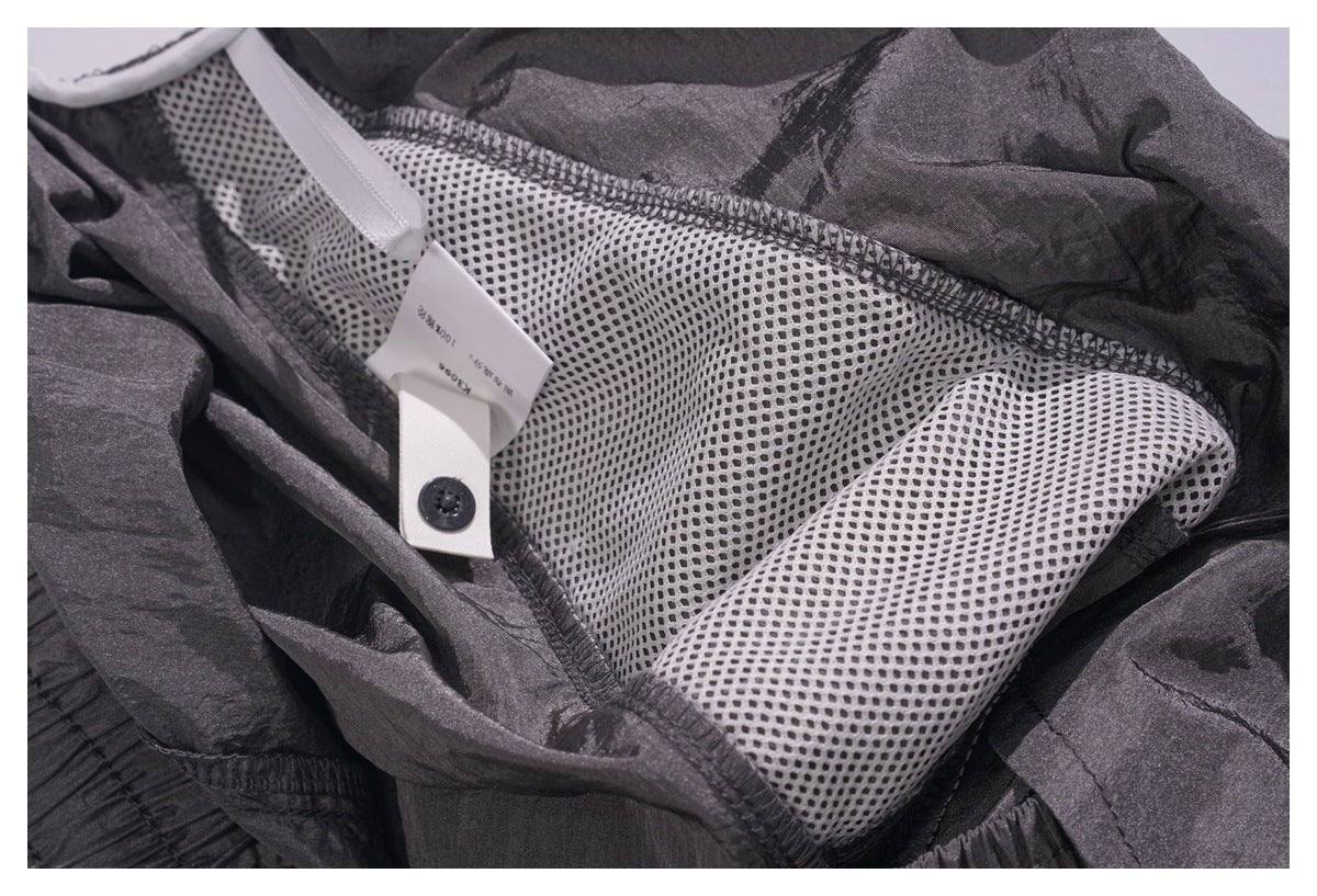 Close-up of white mesh lining, stitching, and a small care label inside a dark charcoal garment.