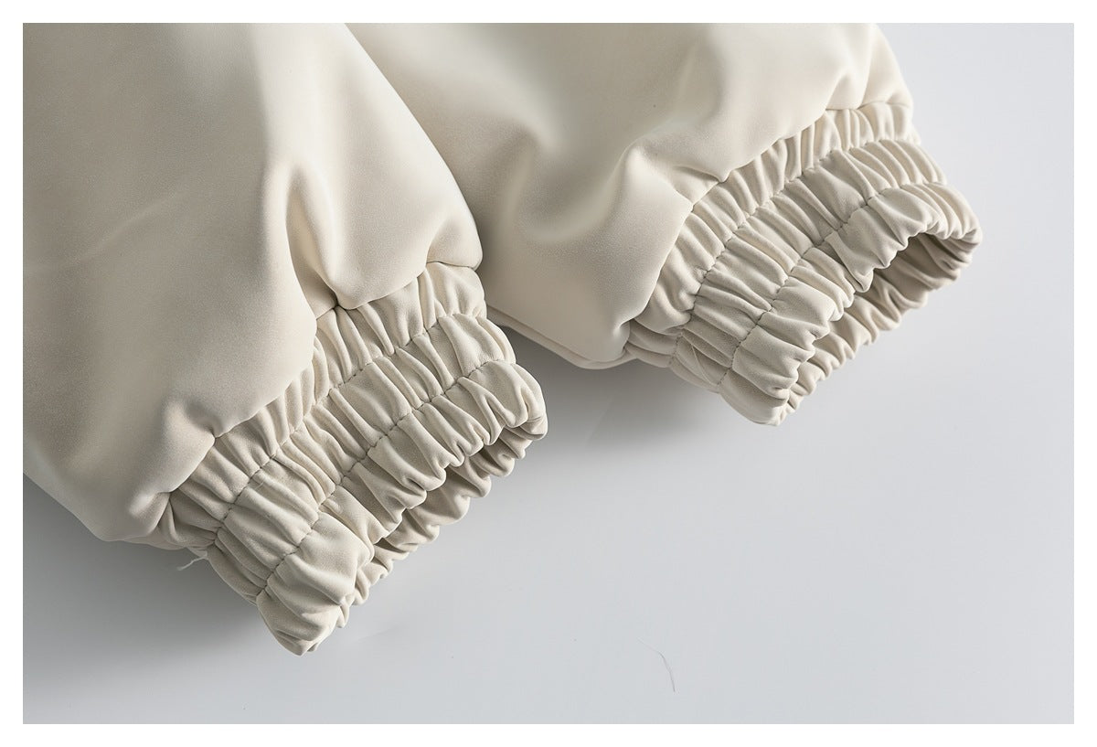 Close-up of two gathered elasticized sleeve cuffs on an ivory coat.