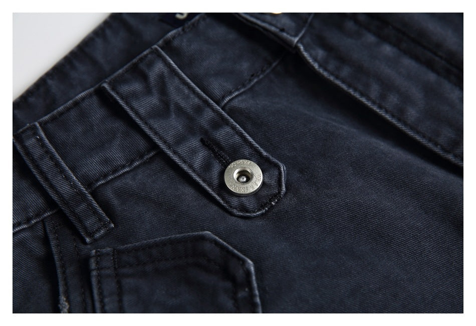 Close-up of a dark charcoal jeans waistband tab with a metal button and visible stitching.