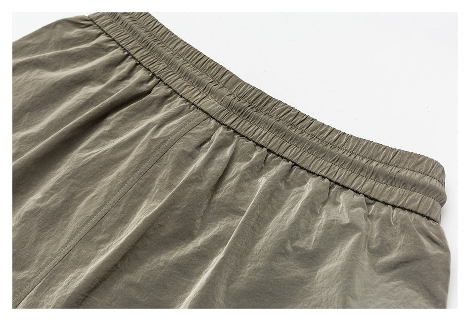 Close-up of the gray-green shorts' gathered elastic waistband and stitched seams.
