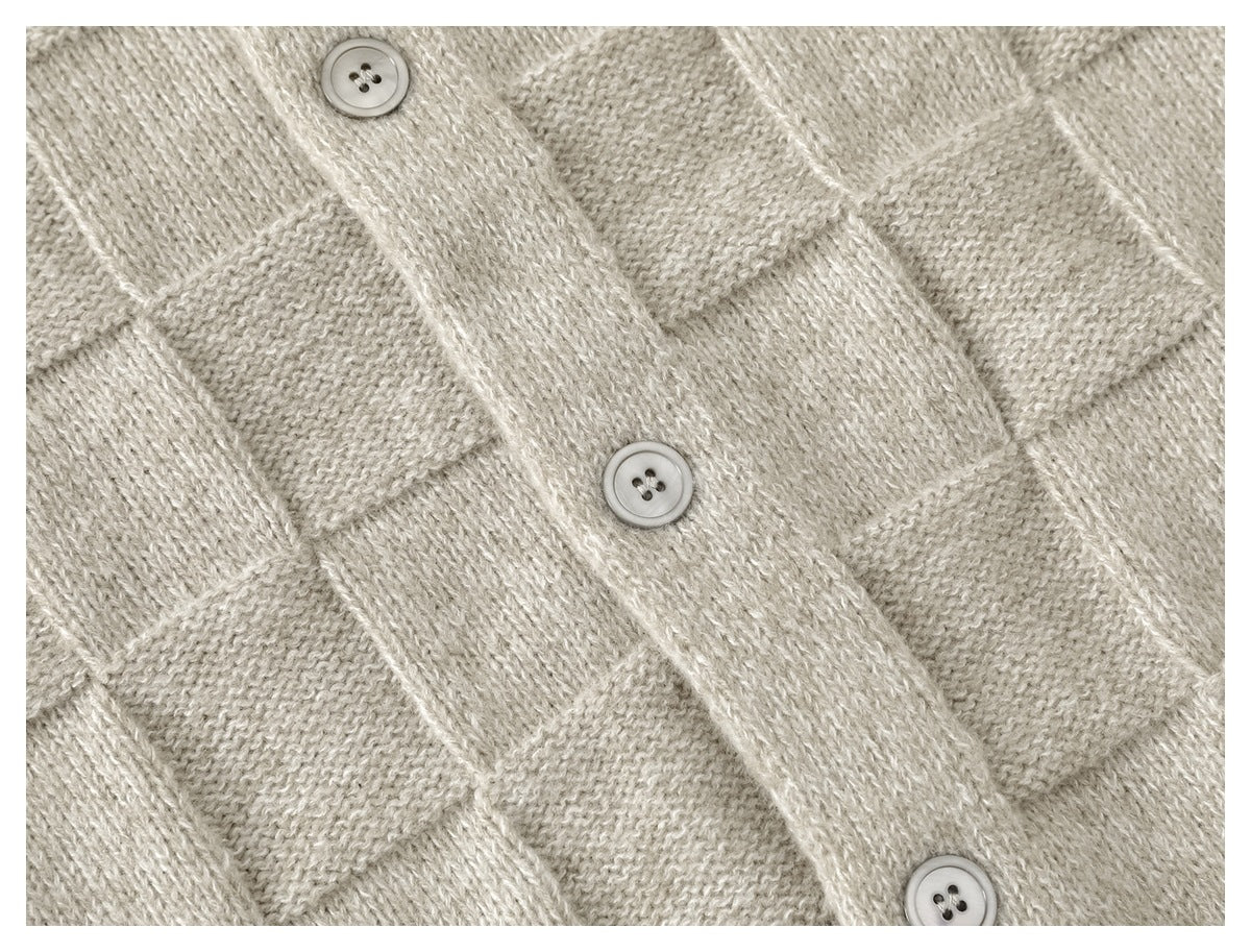 Close-up of the cardigan’s beige checkerboard knit and three light buttons on the front placket.