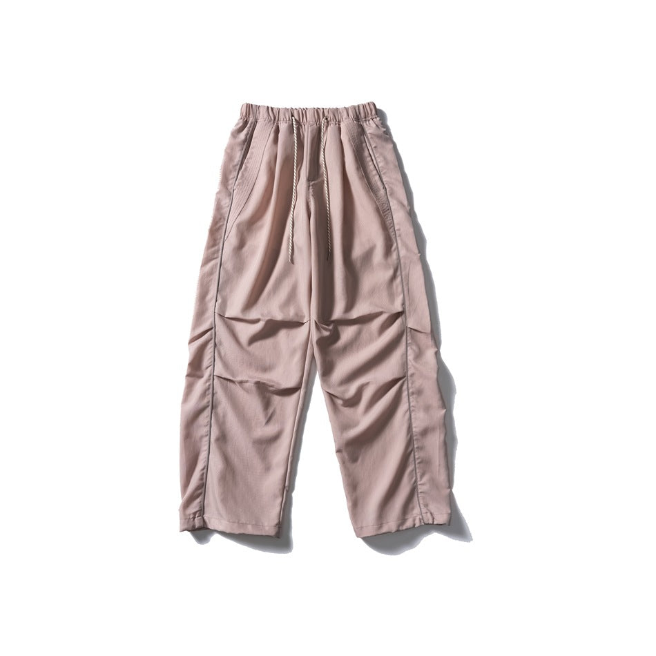 Dusty pink wide-leg drawstring pants with side piping and knee pleats, flat lay front view