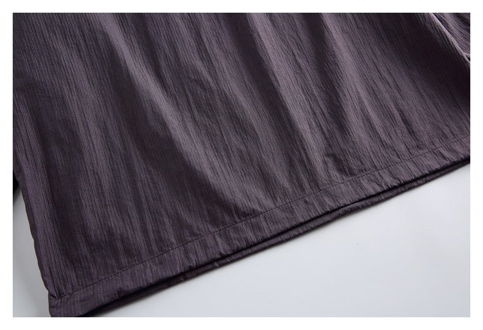 Close-up of the stitched hem on dark plum crinkled fabric.