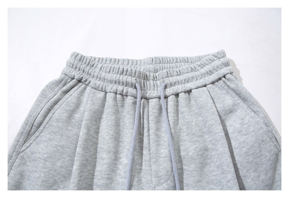 Close-up of the gathered elastic waistband and drawstring on light gray wide-leg sweatpants.