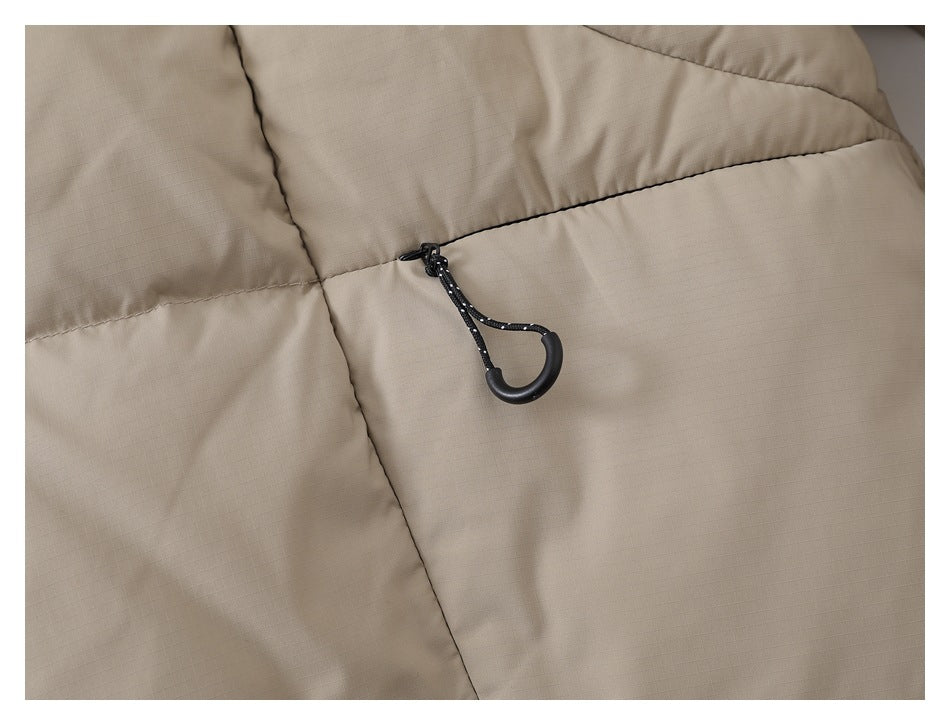 Close-up of a black cord toggle on the taupe jacket's quilted panel.