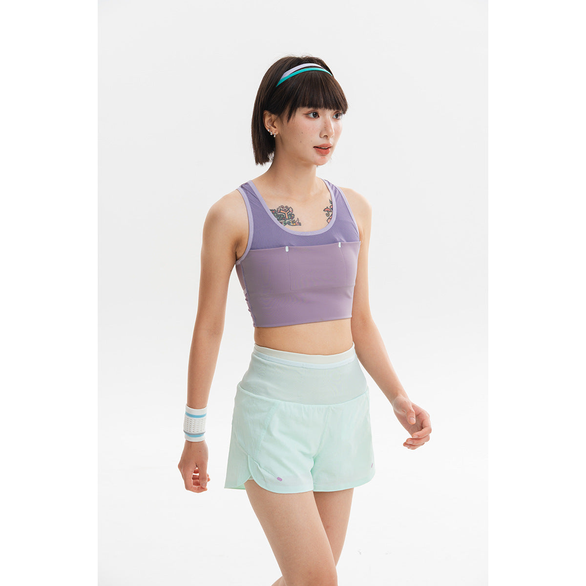 Model wearing a lavender cropped sports top and mint shorts against a white background.