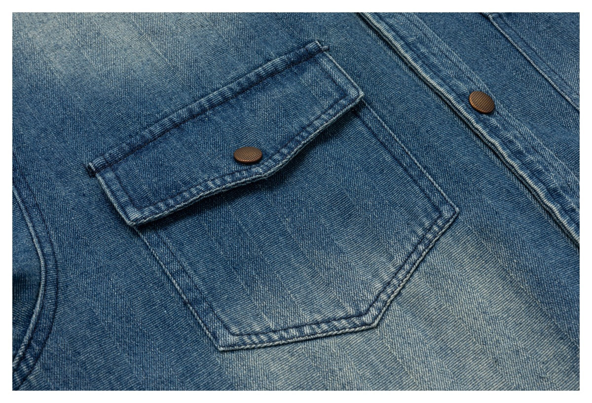 Close-up of a flap chest pocket and brown snap button on the blue denim shirt jacket.