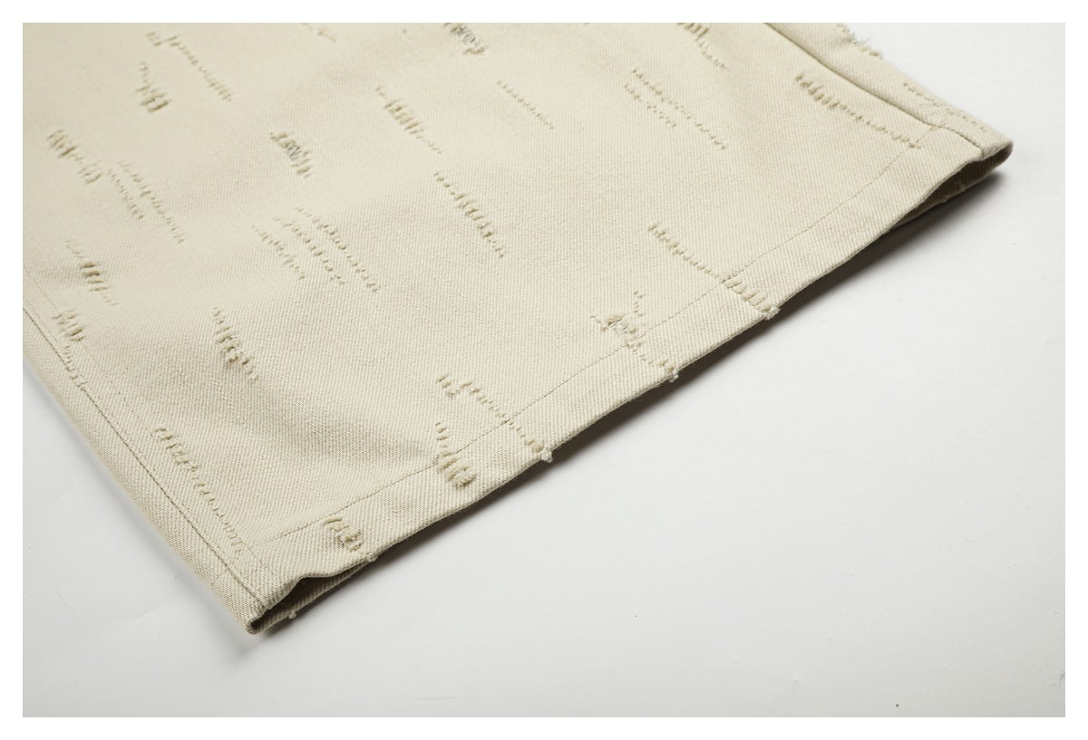 Close-up of the cream trousers' stitched hem and raised decorative stitch pattern.