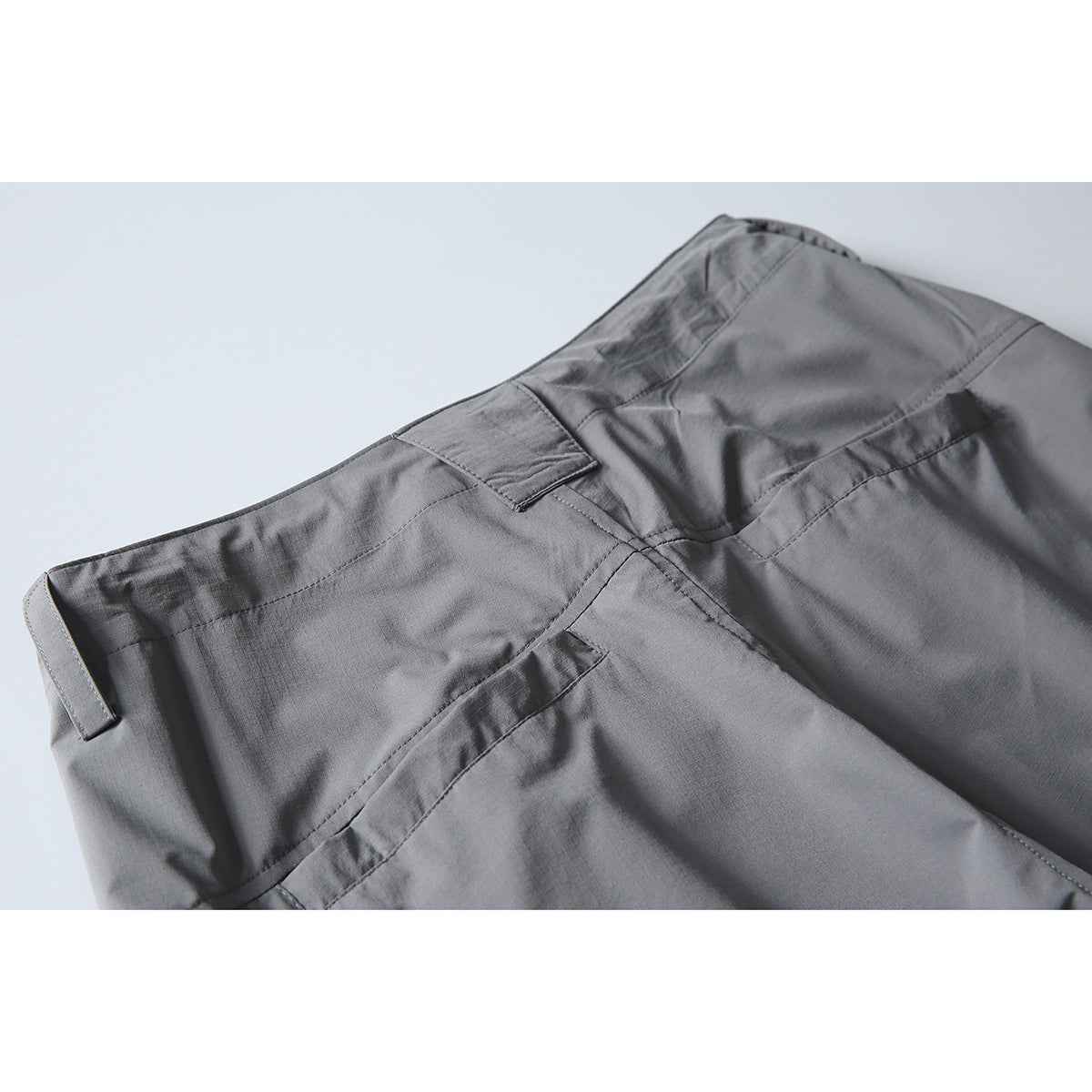 Close-up of the back waistband and seams of gray cargo pants.