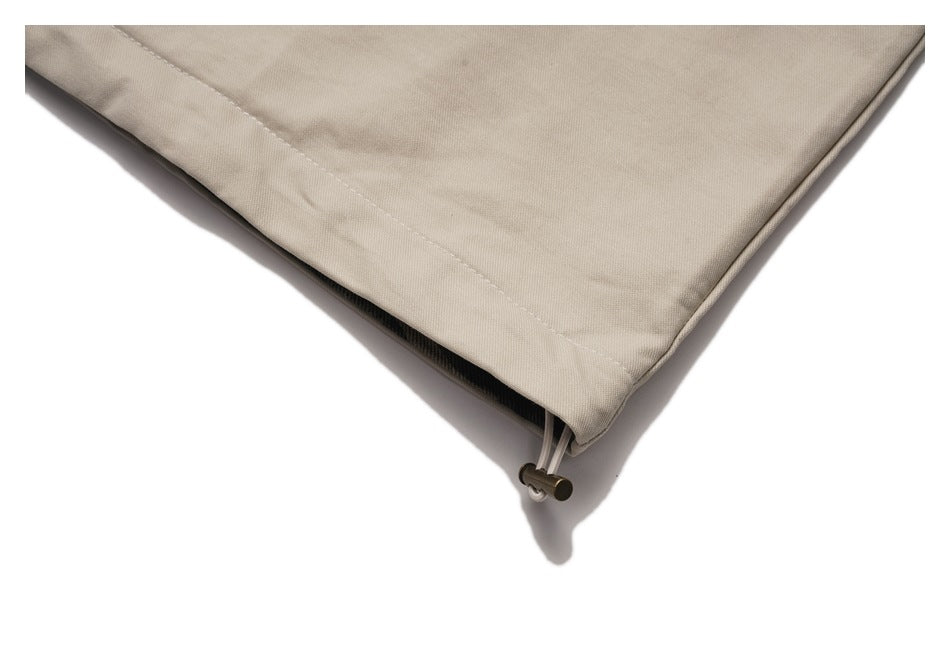 Close-up of the beige jacket hem with a cord and metal toggle for adjustment.