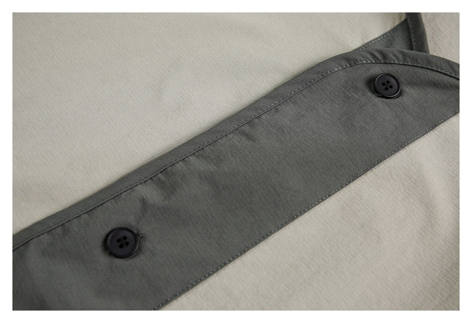 Close-up of a dark gray buttoned trim strip crossing light gray fabric.