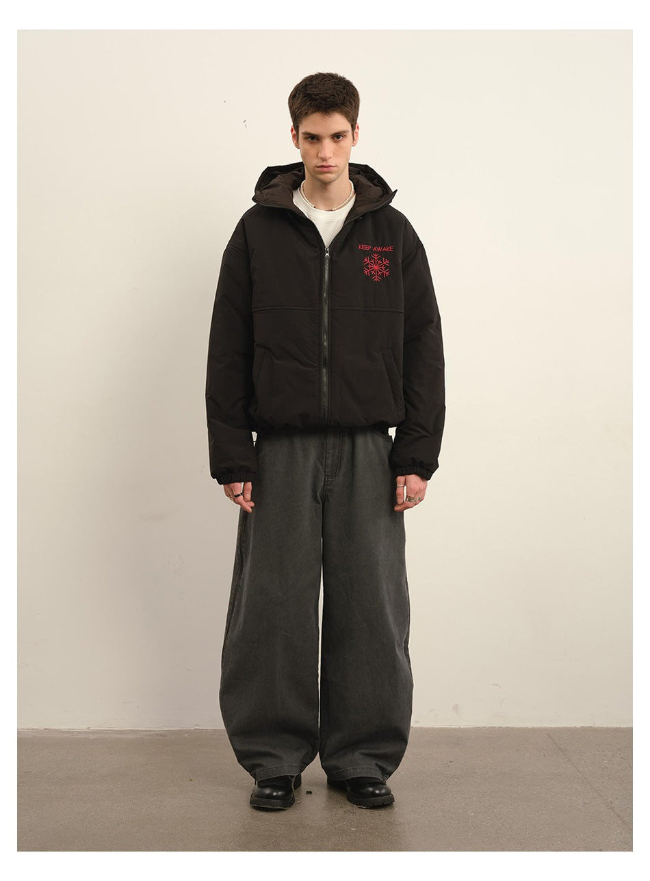 Model wearing the black hooded zip jacket with red snowflake embroidery over a white tee and wide gray pants, front view