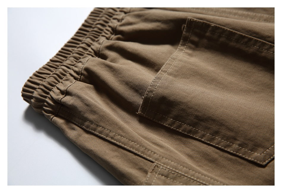 Close-up of brown trousers showing an elasticated waistband, patch pocket and stitching.