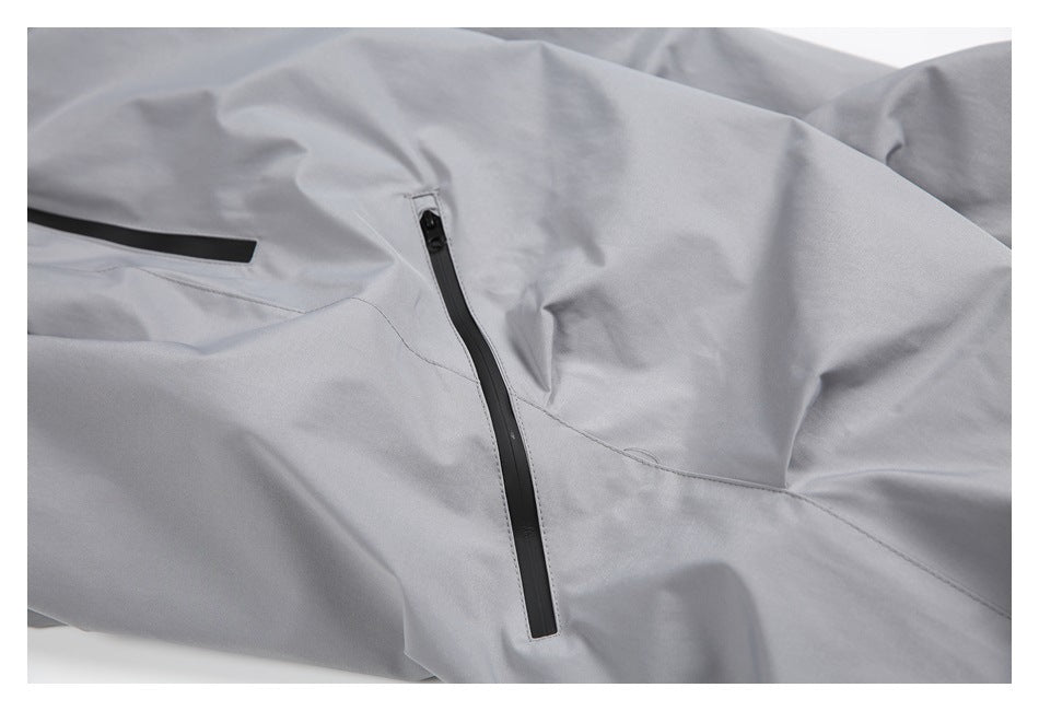 Close-up of light gray trousers showing two black-trimmed zip pockets.