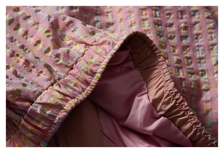 Close-up of a pink plaid garment opened to show its pink lining and gathered inner edge.
