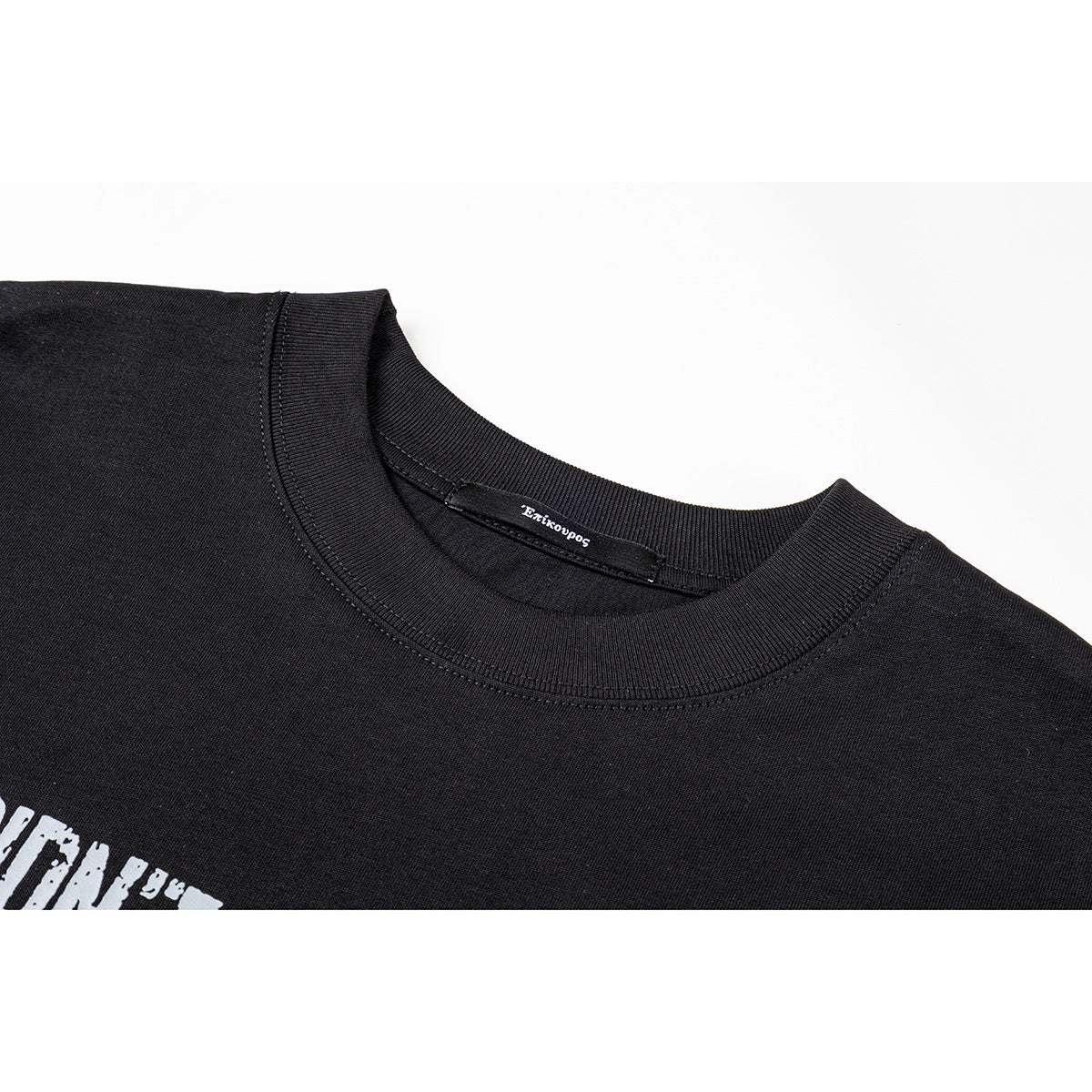 Close-up of a black crew-neck shirt showing the ribbed collar, inner neck label, and part of a white graphic.