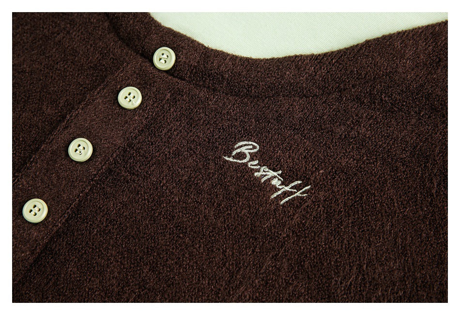 Close-up of a dark brown fuzzy top with pale buttons and white cursive “Beautiful” embroidery.