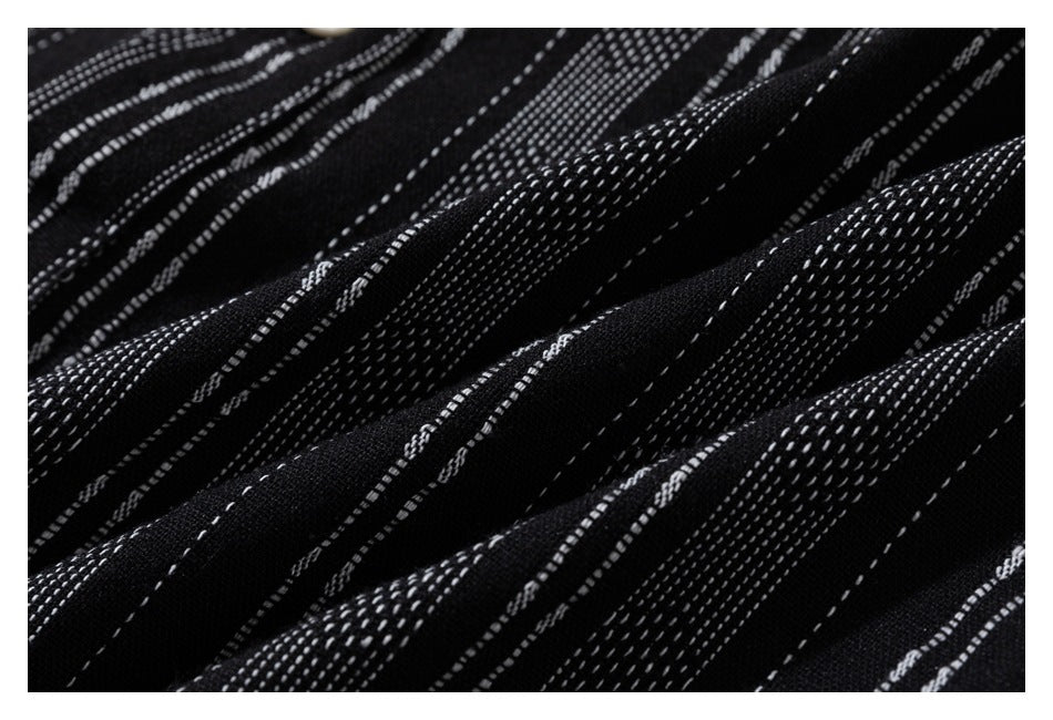Macro view of black fabric with irregular white dashed stripes and a textured woven appearance.