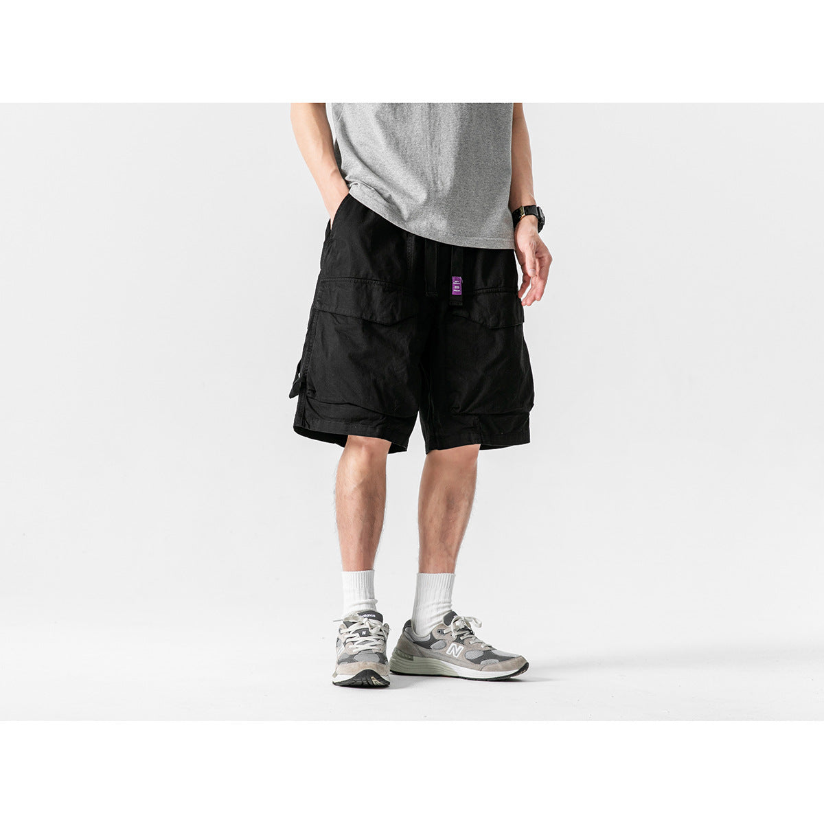 Front view of a model wearing black cargo shorts with roomy flap pockets and a gray T-shirt.