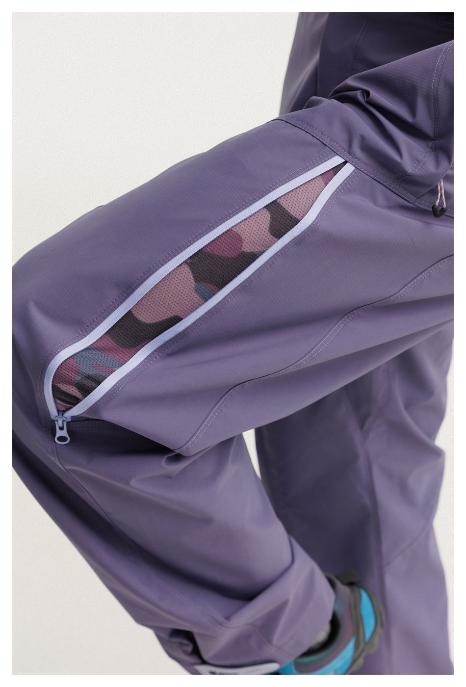 Close-up of purple pants showing a zippered thigh vent with mesh and patterned fabric beneath.