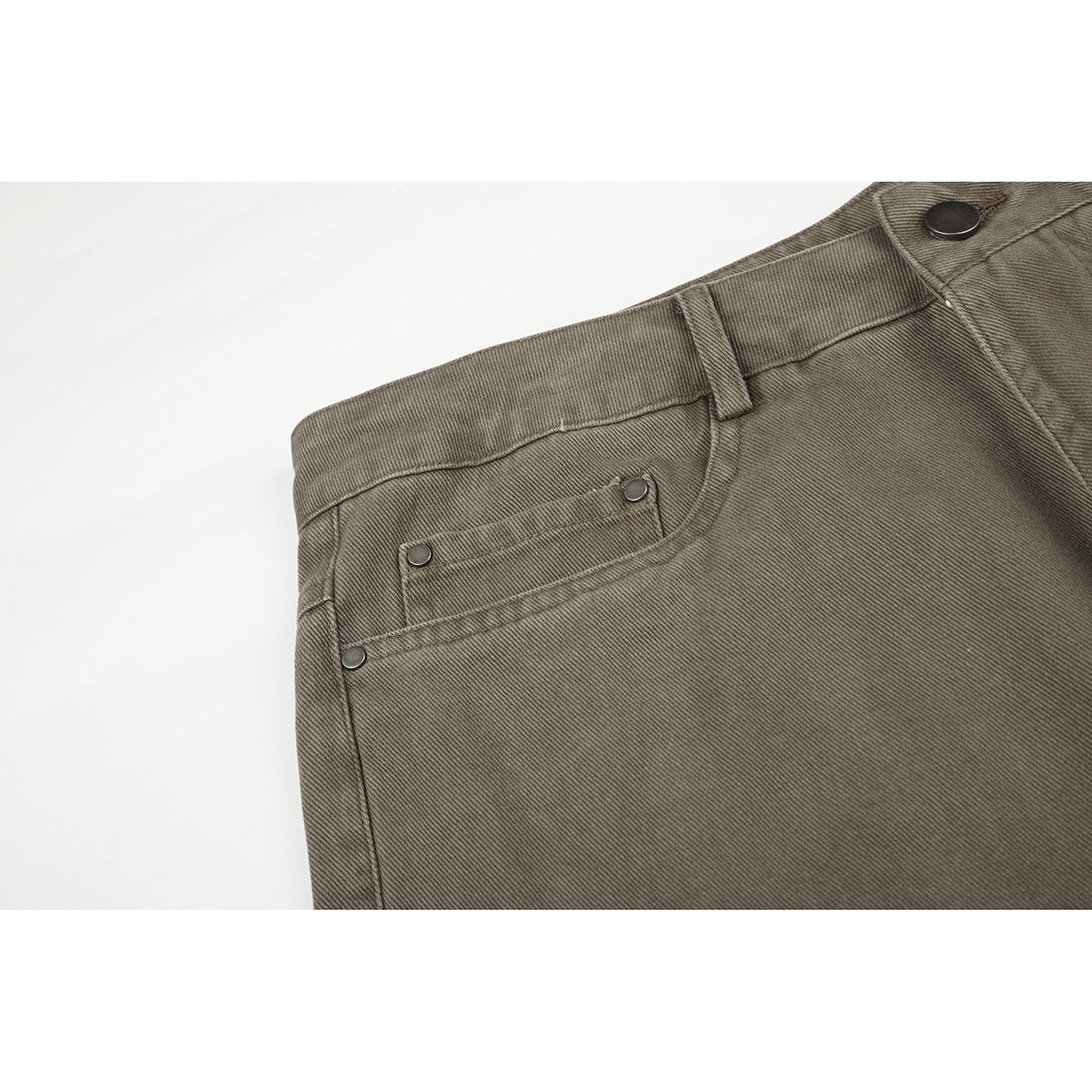 Close-up of taupe-gray pants showing the waistband, button, belt loop, and front coin pocket with metal rivets.