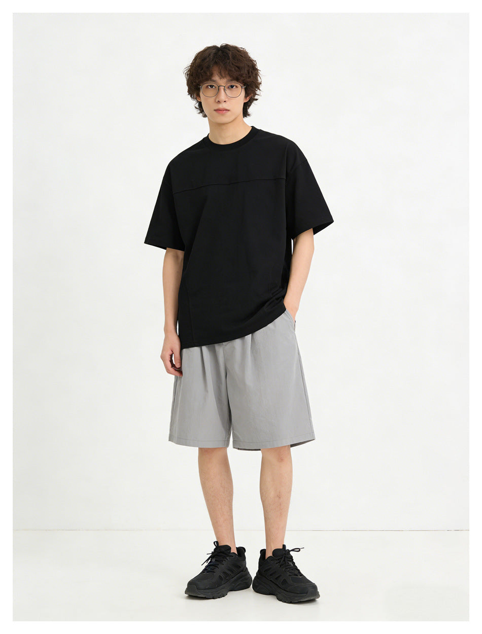 Model wearing a black oversized short-sleeve crewneck T-shirt with a horizontal chest seam.