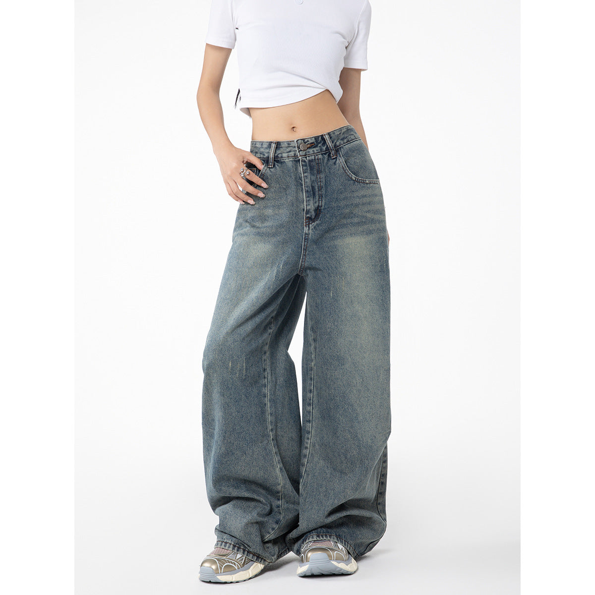 Cropped view of a model wearing faded blue wide-leg jeans, showing the front waistband and legs.