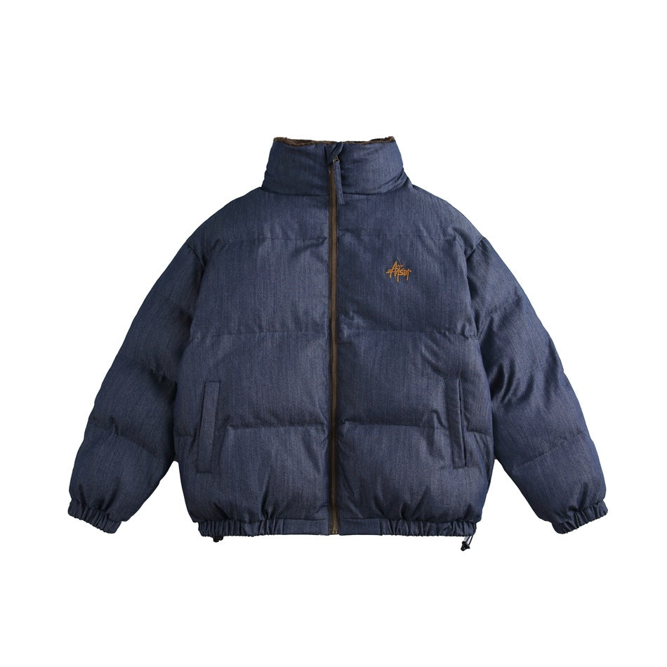 Denim blue puffer-style jacket with stand collar, front zip, slanted pockets, elastic cuffs and chest embroidery, front view