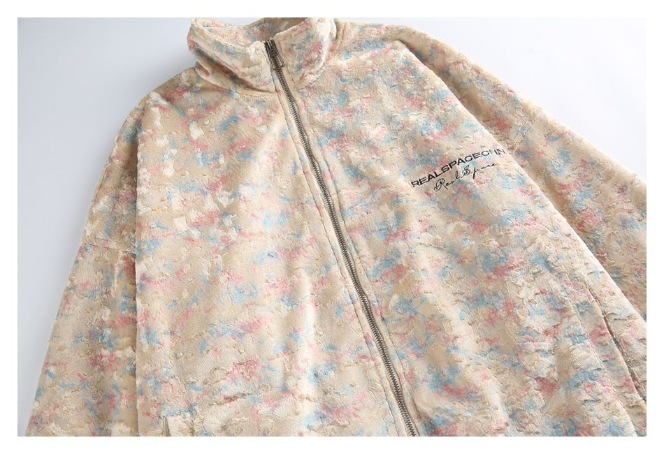 Flat lay of a cream zip-front jacket with a raised pastel pink and blue pattern and chest lettering.