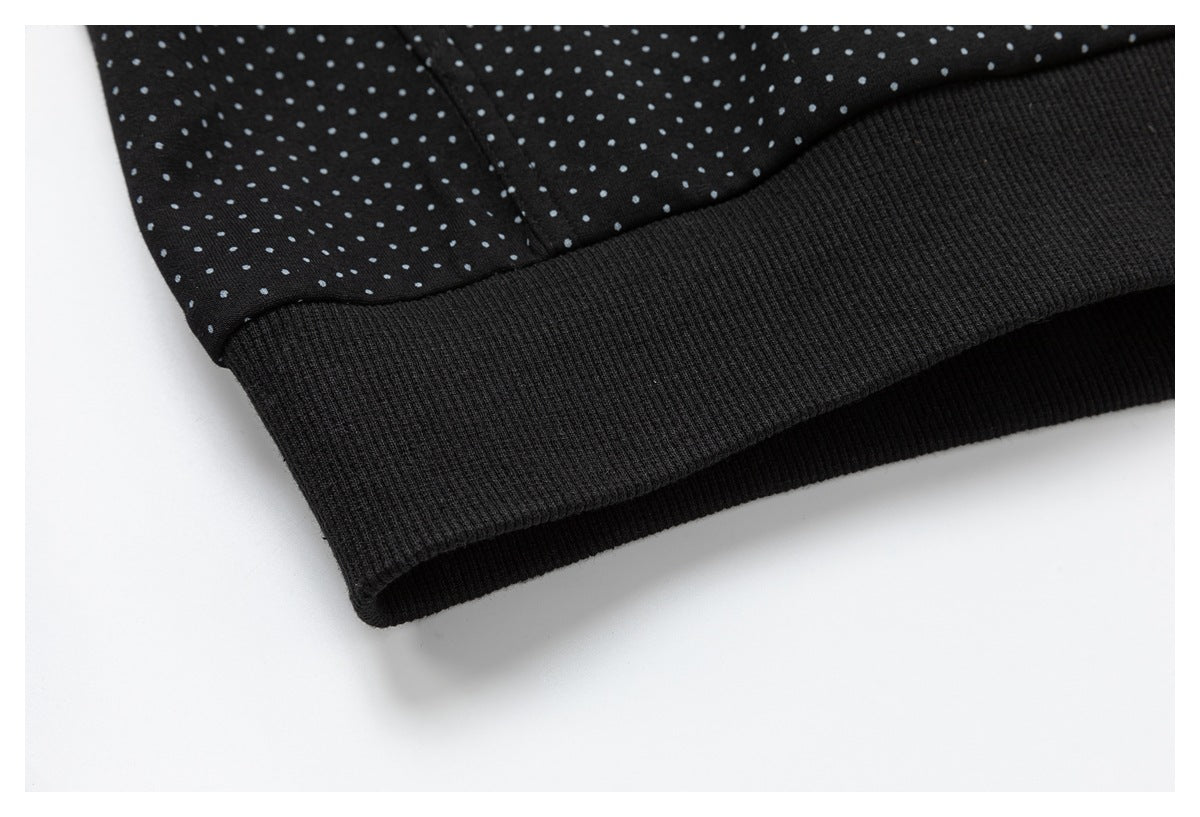 Close-up of a wide black ribbed hem on a black garment with small gray dots.