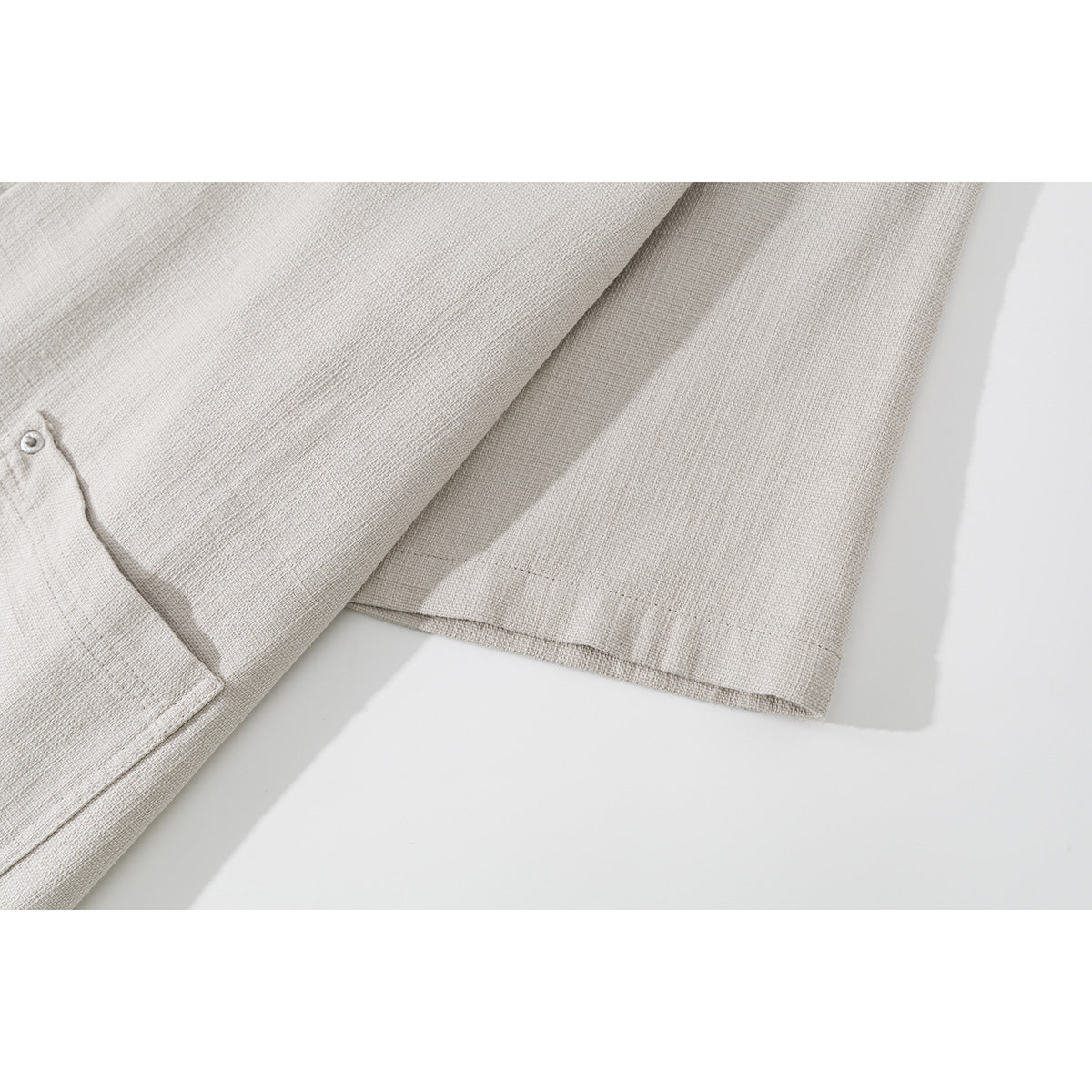 Close-up of the light beige shirt's short sleeve, hem stitching, and textured surface.