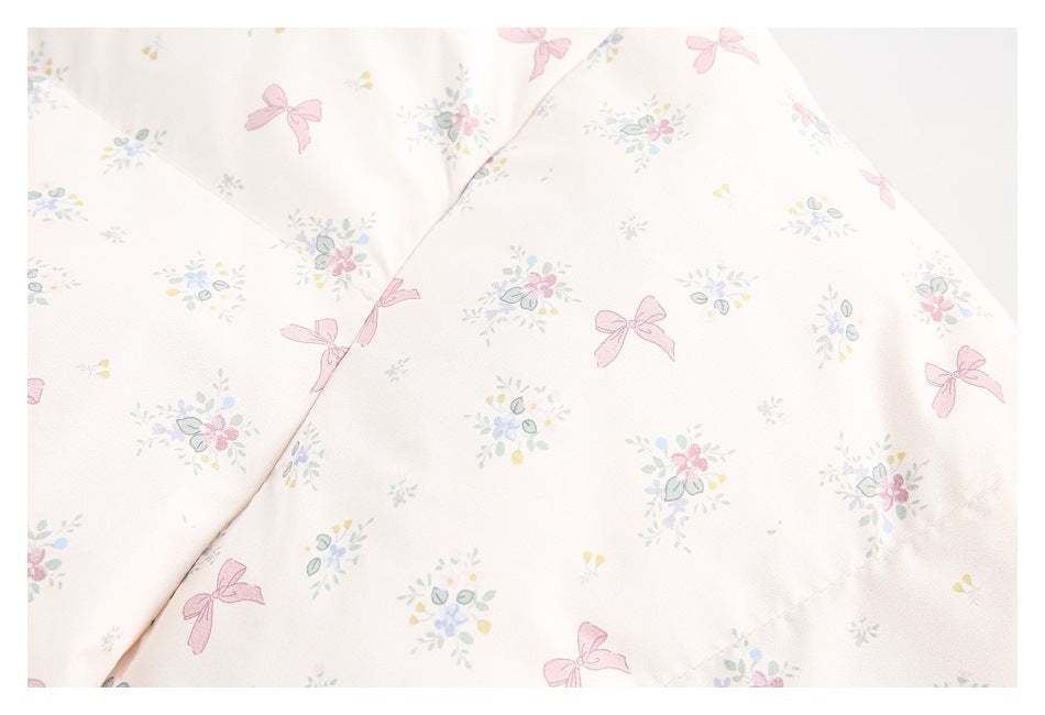 Close-up of pale pink fabric printed with small flowers and pink bows, showing a curved stitched seam.
